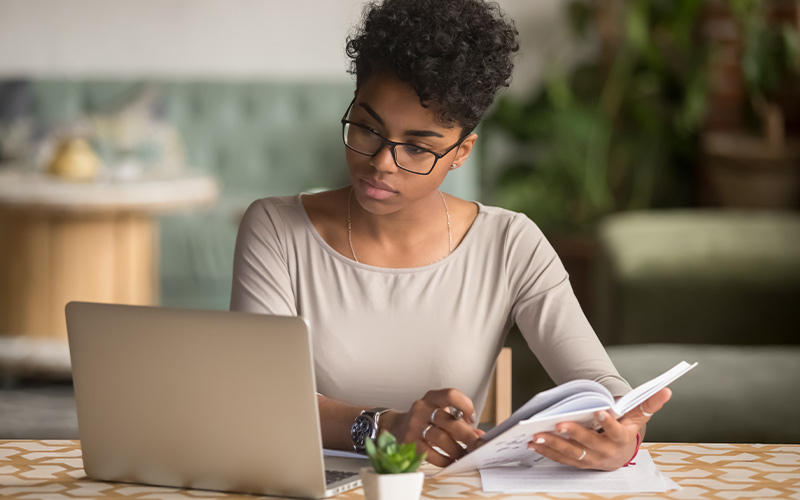 Woman taking notes while working on a laptop