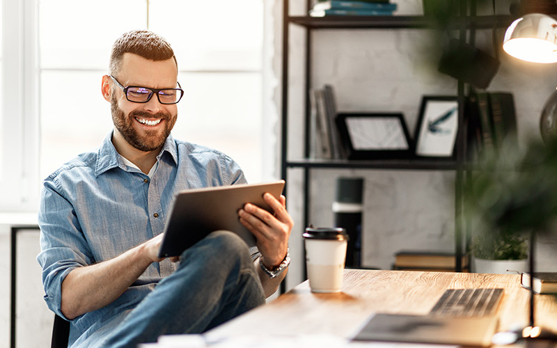 Man smiling while using a tablet