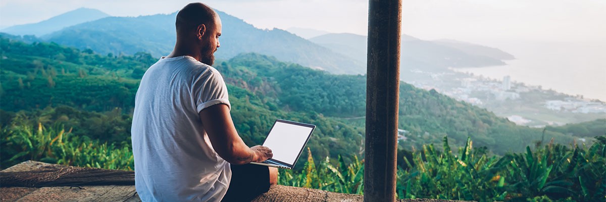 Rear view of male traveler blogger work remote on netbook computer while enjoying amazon nature landscape view outdoors. 