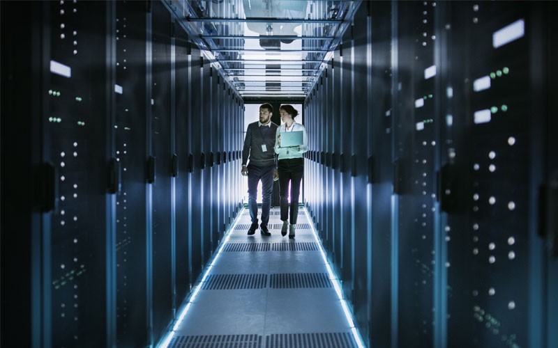 Ensure essential data protection  Two technicians walking through a data centre