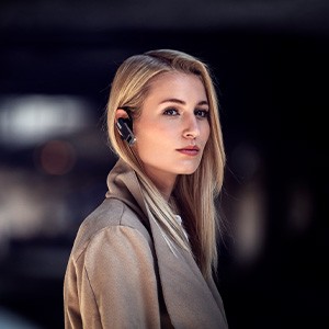 Stylish young woman uses earpiece outdoors