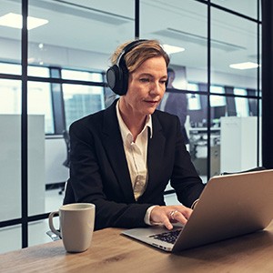 Female worker uses headphones whilst using a laptop