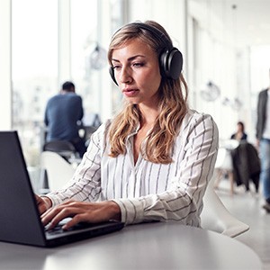 Enjoy Versatile Usage Young female office worker using a Sennheiser headset