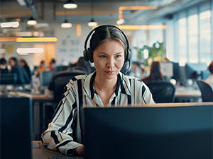 Male worker uses his headset in front of a laptop at night