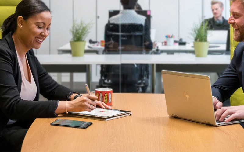 Two colleagues using HP devices in a meeting