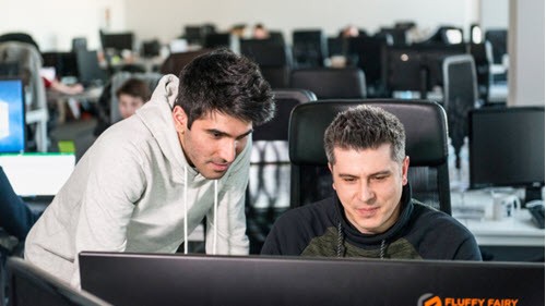 two infrastructure managers collaborate together in front of desktop screen two infrastructure managers collaborate together in front of desktop screen